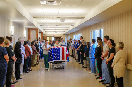 LGH staff line the hallways while the gurney, draped in an American flag, is wheeled through the hallways.